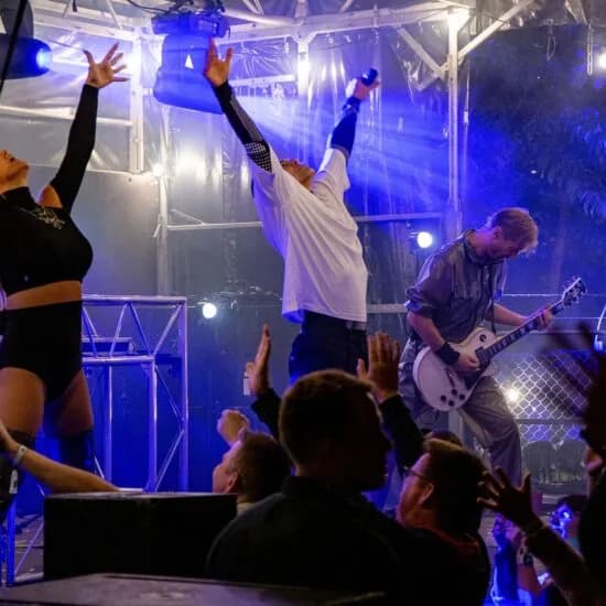 Band på en udendørs scene i blåt lys med publikum foran