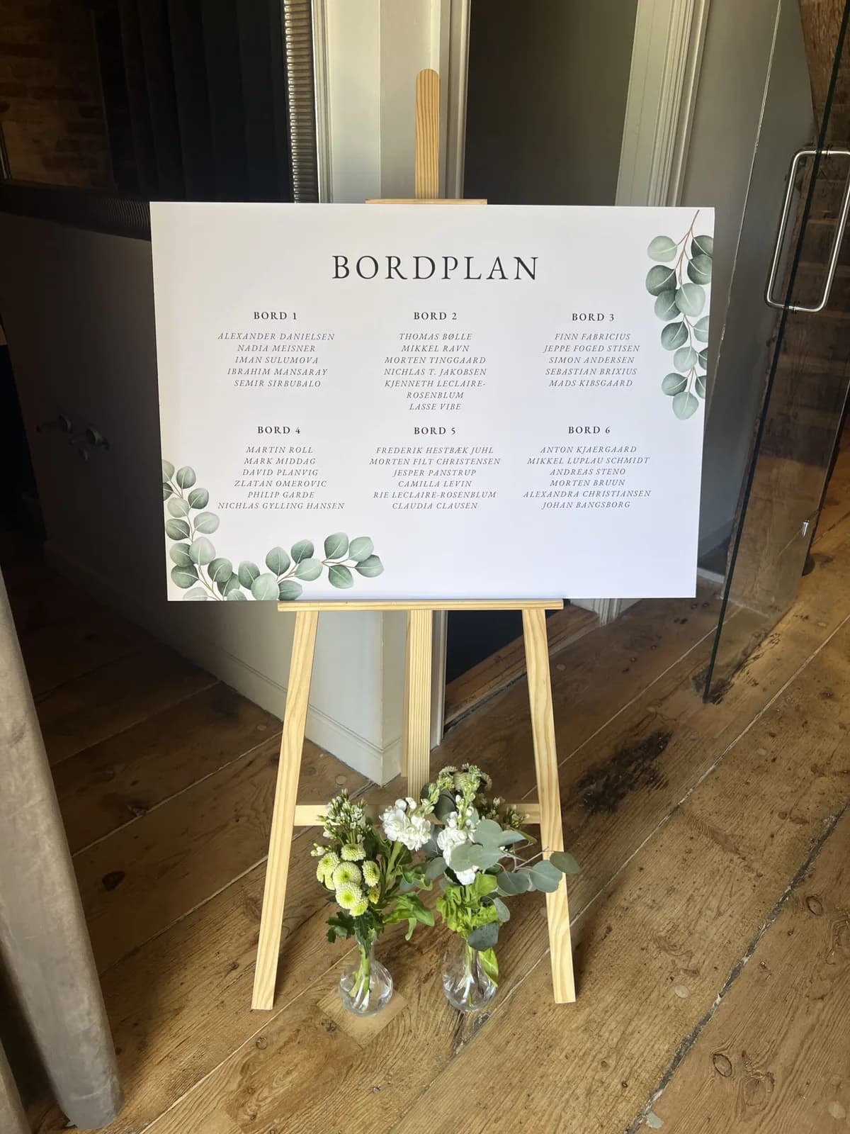 Bordplan på et staffeli med blomster ved foden