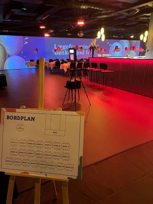 Bordplan på et staffeli ved indgangen til et lokale i rødt og blåt lys