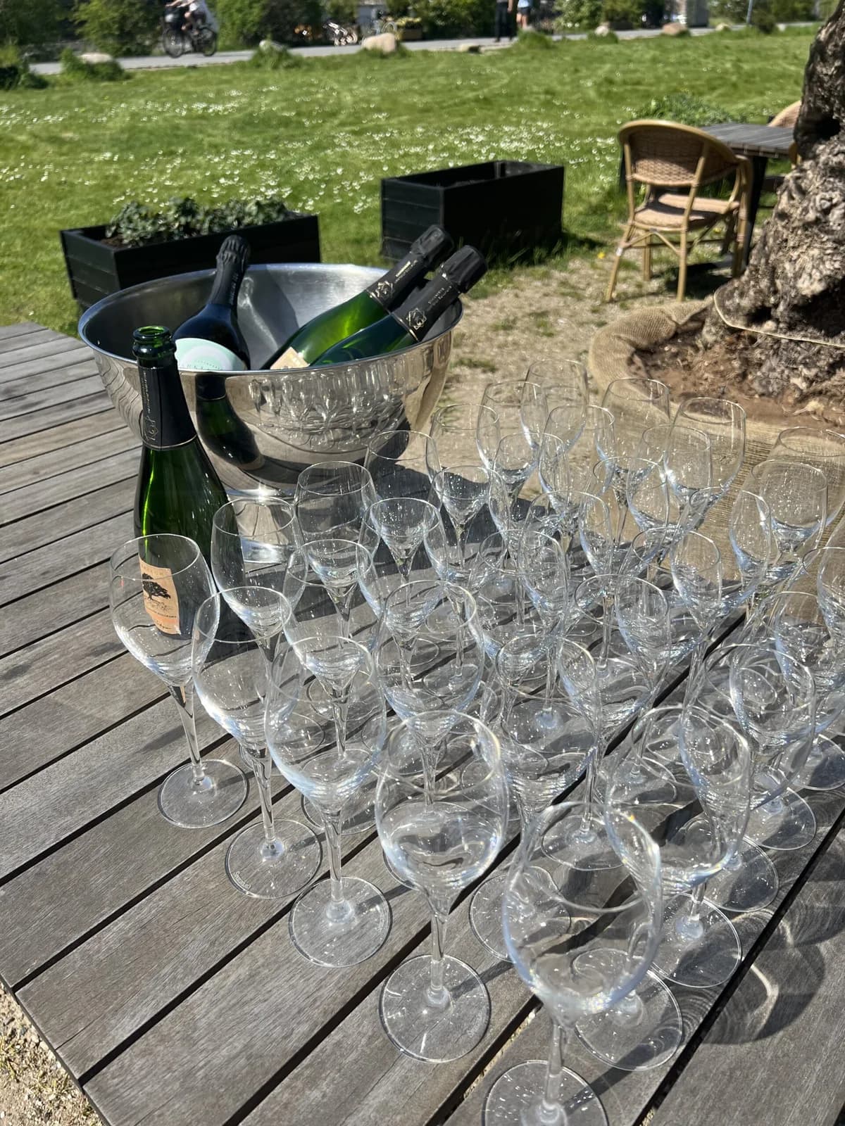 Champagne på køl og glas stillet frem på en træterrasse