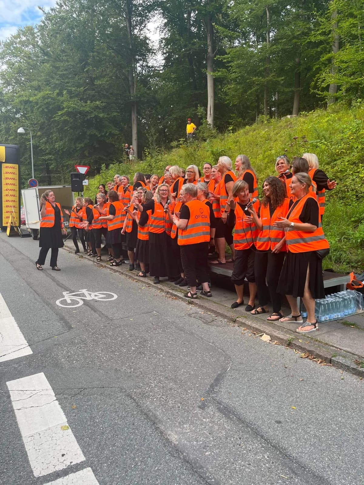 Kor i orange veste synger langs ruten