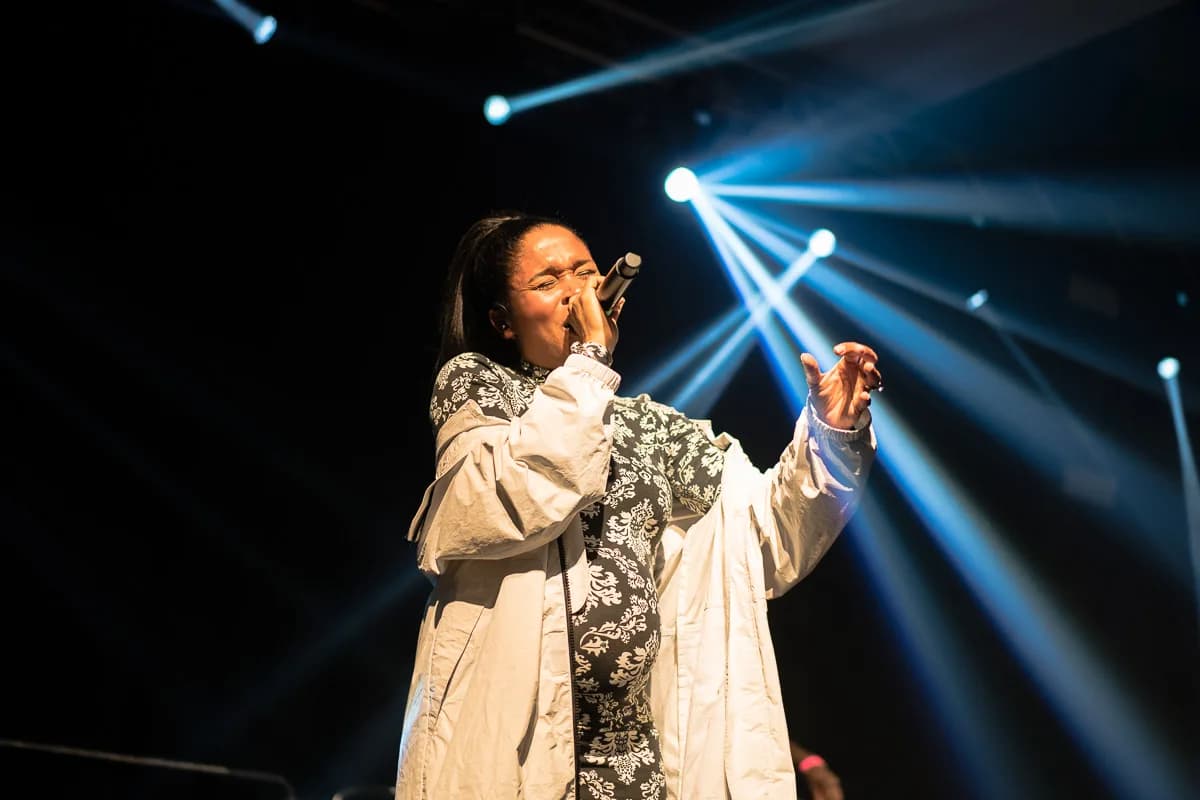 Sanger på scenen i blåt og hvidt lys foran publikum