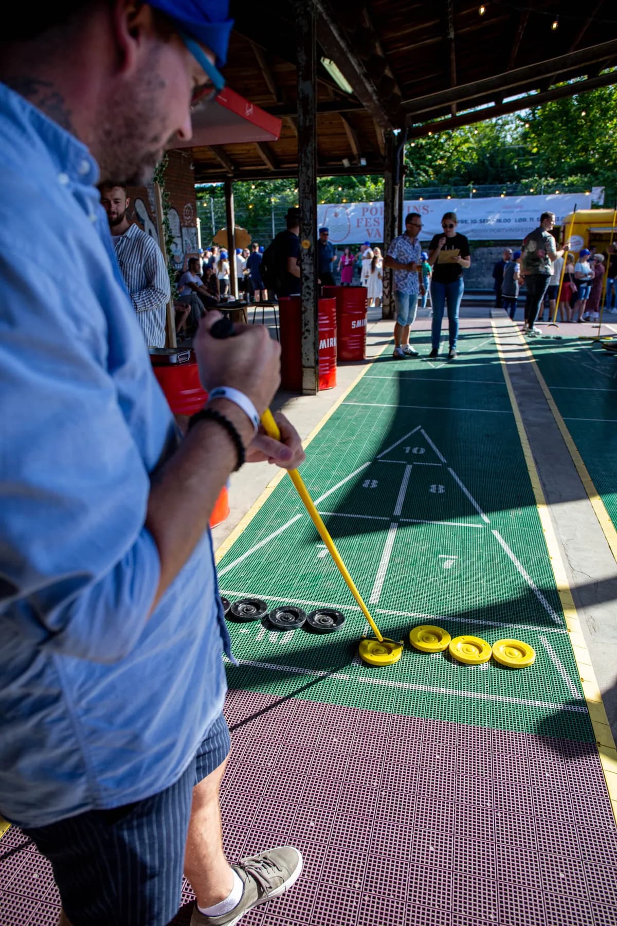 Deltager spiller shuffleboard på en udendørs bane