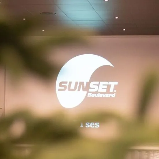 Lærred med Sunset Boulevards logo set gennem grønne grene