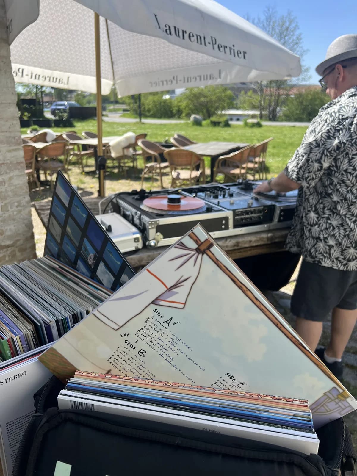 DJ med vinylplader under en parasol på terrassen